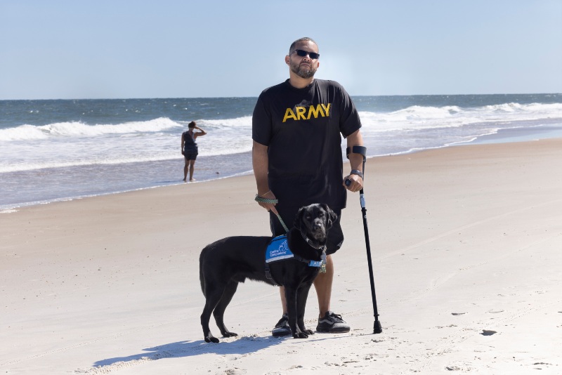 man and dog standing on the beach